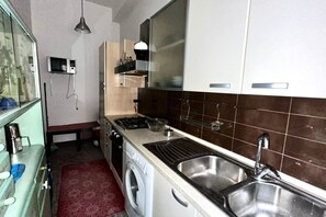 A compact kitchen with a washing machine, a sink, and a microwave.