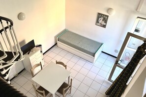 Une petite pièce avec un lit, une table et une chaise.