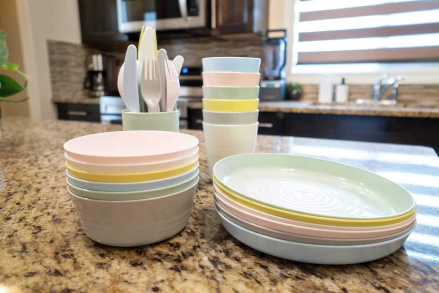 A kitchen counter with stacked plates and a utensil holder.