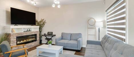 A modern living room with a fireplace, a flat-screen TV, a sofa, and a coffee table.