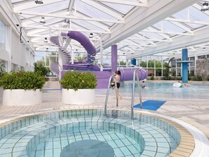 An indoor swimming pool with a slide and a water feature. - 6 Person Holiday Home on a Holiday Park in Hanstholm (Hanstholm)
