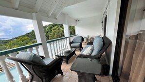 A balcony with wicker furniture, a view of greenery, and a pool. - 2bed 2 bath with Shared Pool and a View. 7 mins to Cruz Bay! 15 mins to Beaches. (St. John)