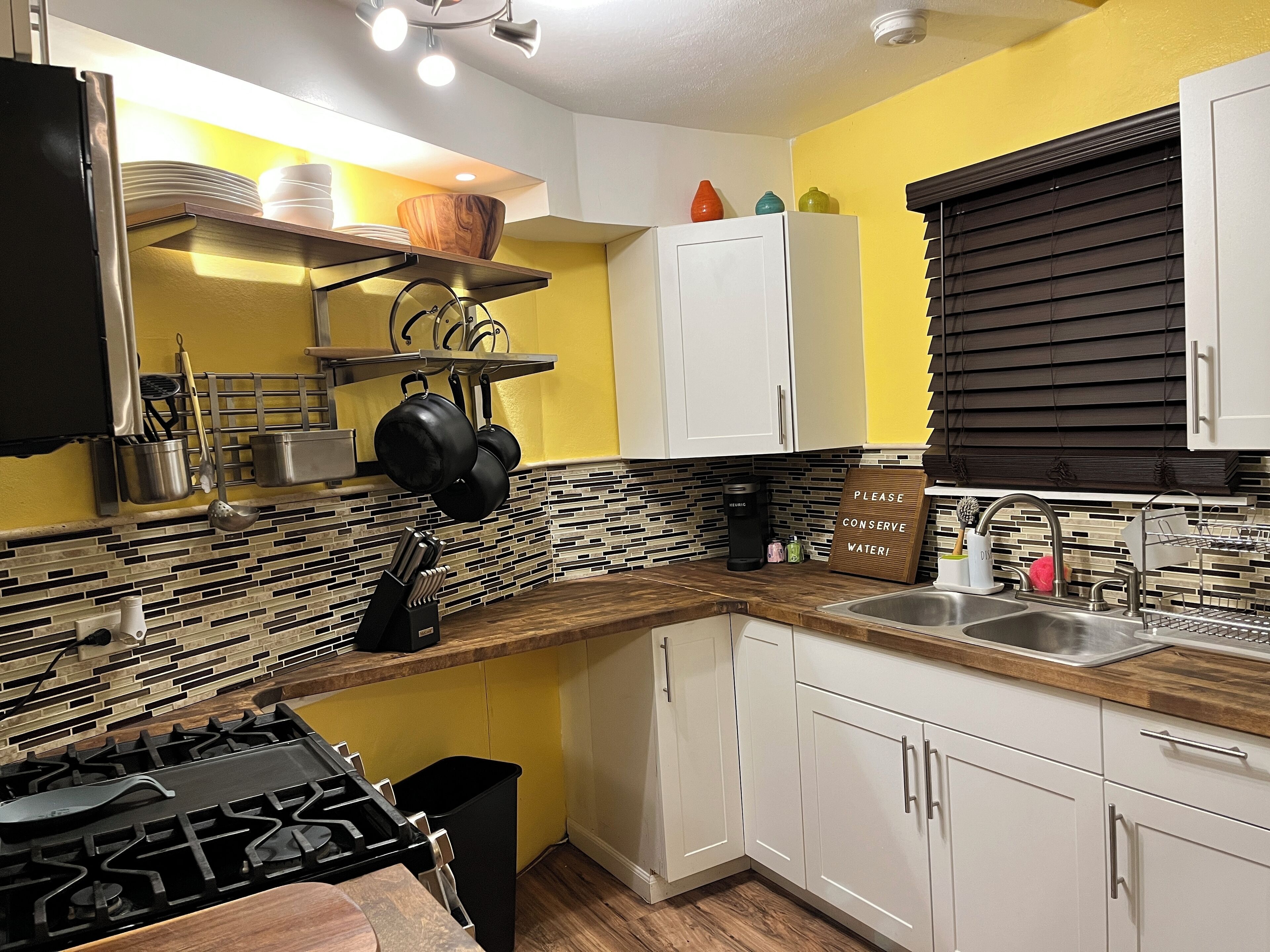A kitchen with white cabinets, a black stove, and a sink.