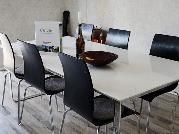 A conference room with a white table, black chairs, a sign, a candle, and a bottle. - 4 Star Holiday Home in Halmstad (Halmstad)