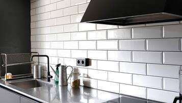 A kitchen with white subway tiles, a black range hood, and stainless steel appliances.