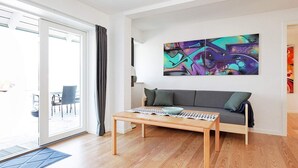 A modern living room with a grey sofa, a wooden coffee table, and a colorful abstract painting on the wall. - 8 Person Holiday Home on a Holiday Park in Karrebaeksminde (Karrebæksminde)