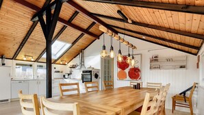 Una cocina amplia con una mesa y sillas de madera, horno empotrado y un ventanal grande.