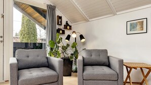 Una sala de estar moderna con dos sillones grises, una mesa de centro de madera y una planta grande en maceta.