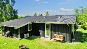 Een laag gebouw met een overdekte veranda, een bank en een kleine tuin.
