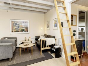 Una sala moderna con un sofá, sillones, una mesa de centro y una escalera.