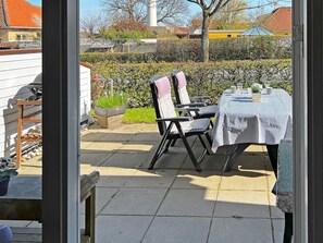 Une terrasse extérieure avec une table et des chaises, un barbecue et une plante en pot.