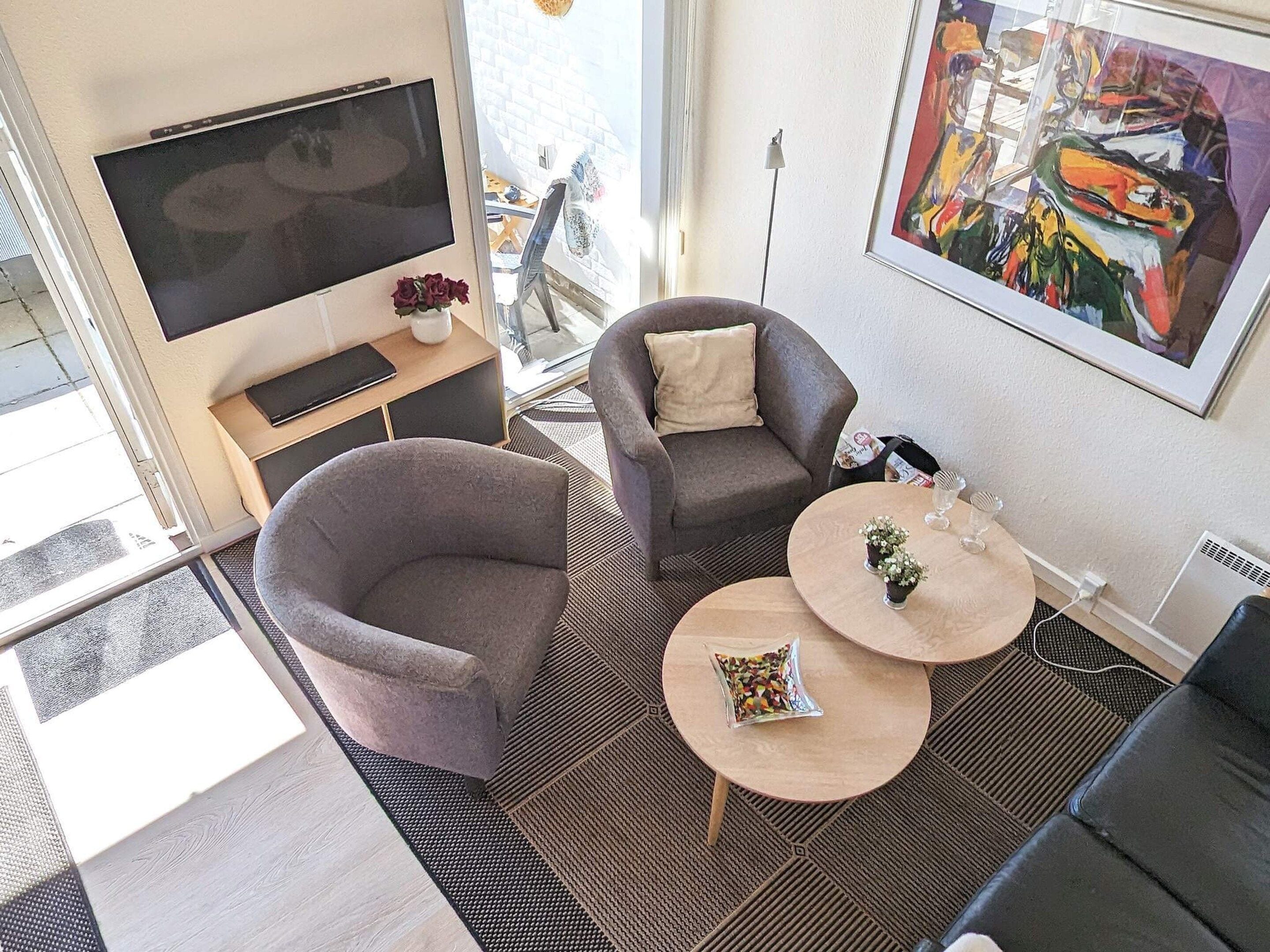A modern living room with a sofa, two coffee tables, a TV, and a painting on the wall.
