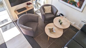 A modern living room with a sofa, two coffee tables, a TV, and a painting on the wall. - 4 Person Holiday Home in Aeroskobing (Aeroskobing)