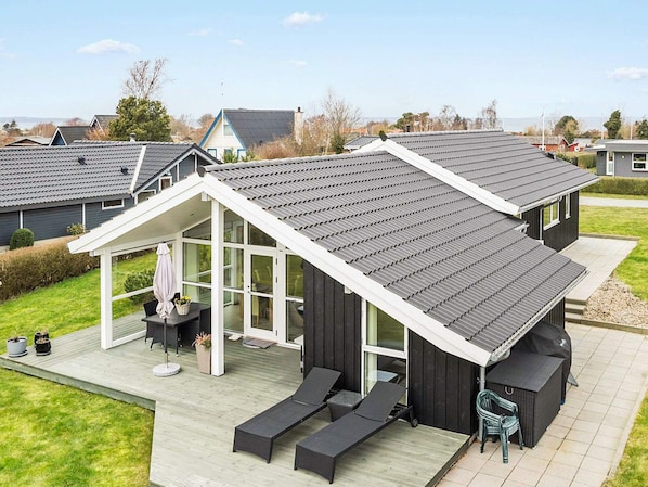 A modern house with a large deck, a covered patio, and a view of the surrounding neighborhood. - 8 Person Holiday Home in Bogense (Bogense)