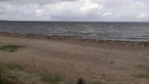 A beach with a sandy shore and a view of the ocean under a cloudy sky.