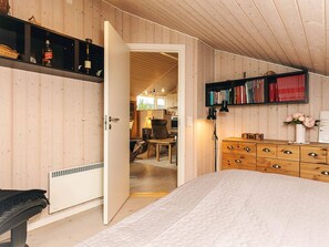 A bedroom with a bed, a dresser, a bookshelf, and a door leading to a dining area. - 8 Person Holiday Home in Bogense (Bogense)