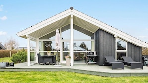 A modern house with a covered patio, outdoor seating, and a barbecue area.