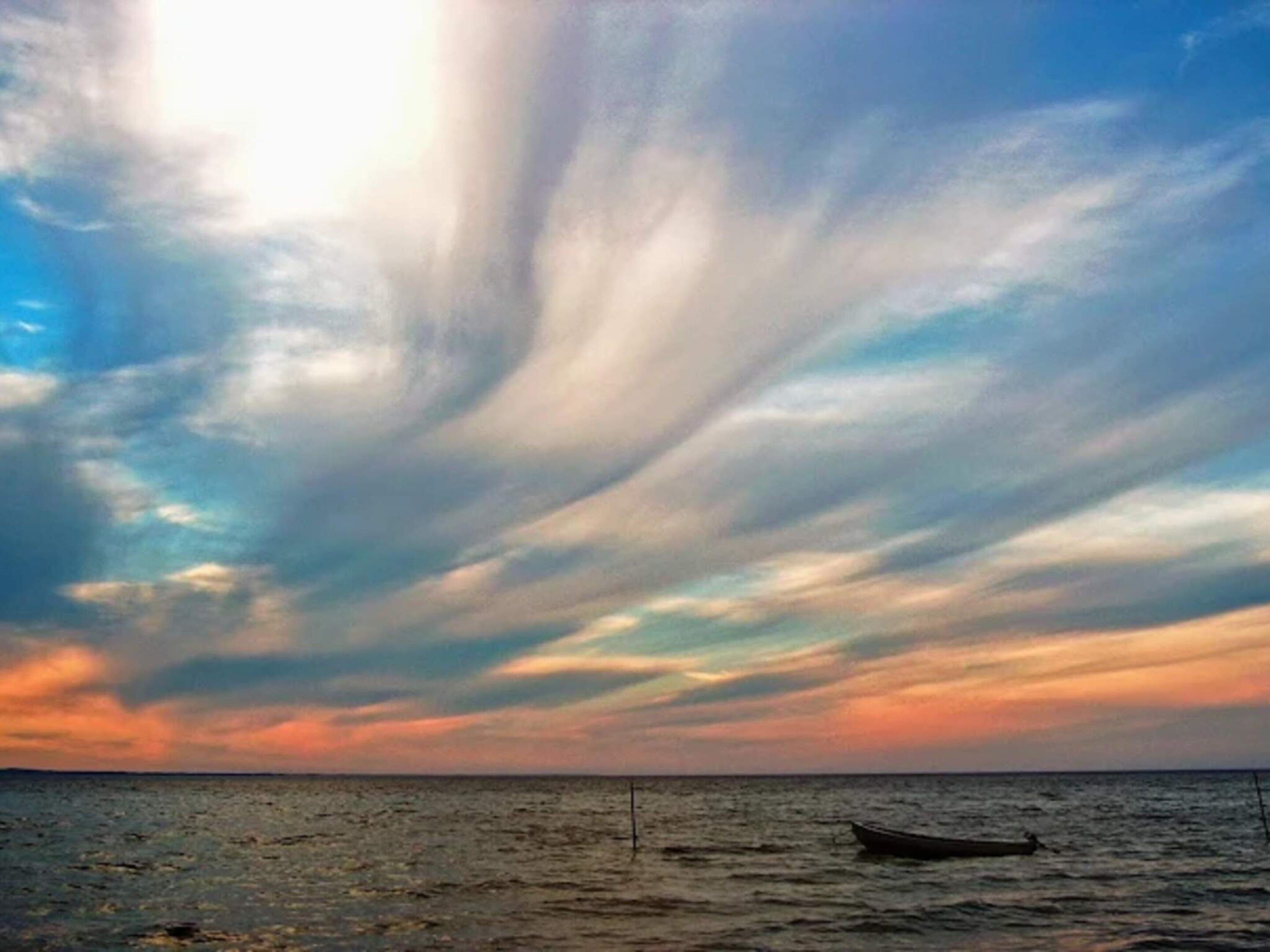 Un atardecer sobre un cuerpo de agua con un bote y una boya.