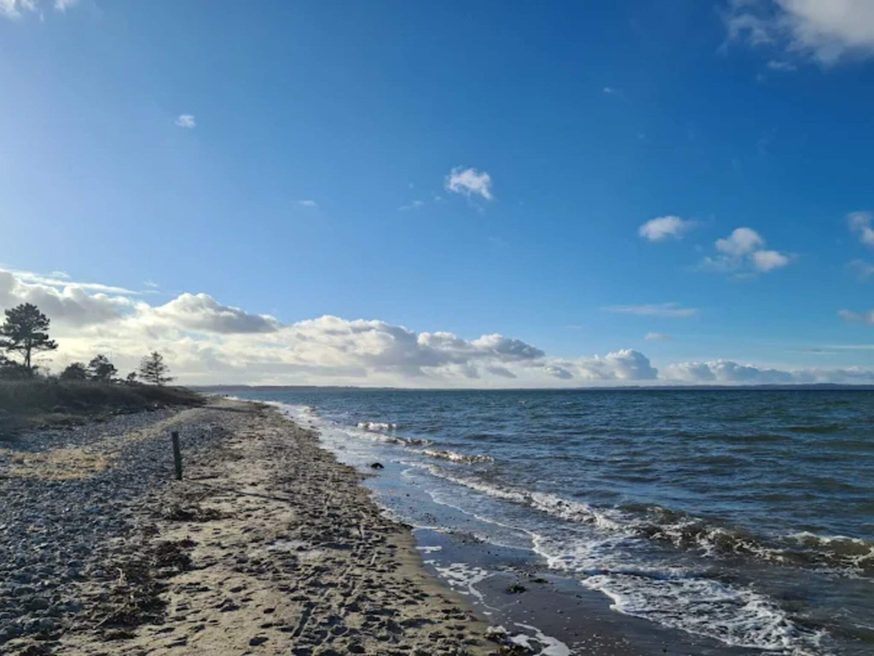 Een strand met zand, golven en een heldere lucht.