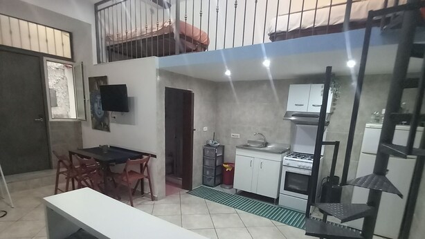 Un grand espace de vie comprenant une table à manger, un canapé et une cuisine en arrière-plan.