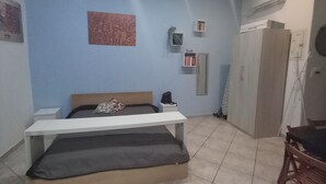 Une chambre à coucher comprenant un lit, une table de chevet et une chaise. Les murs sont décorés et il y a un appareil de climatisation.