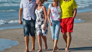 Une famille se promène sur une plage de sable, avec l’océan en arrière-plan.