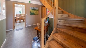 Un escalier en bois avec une rampe en métal, un coin repas avec des chaises et une table, et un tableau accroché au mur.