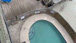 Un área de piscina con terraza de madera, sillas de descanso y una mesa.