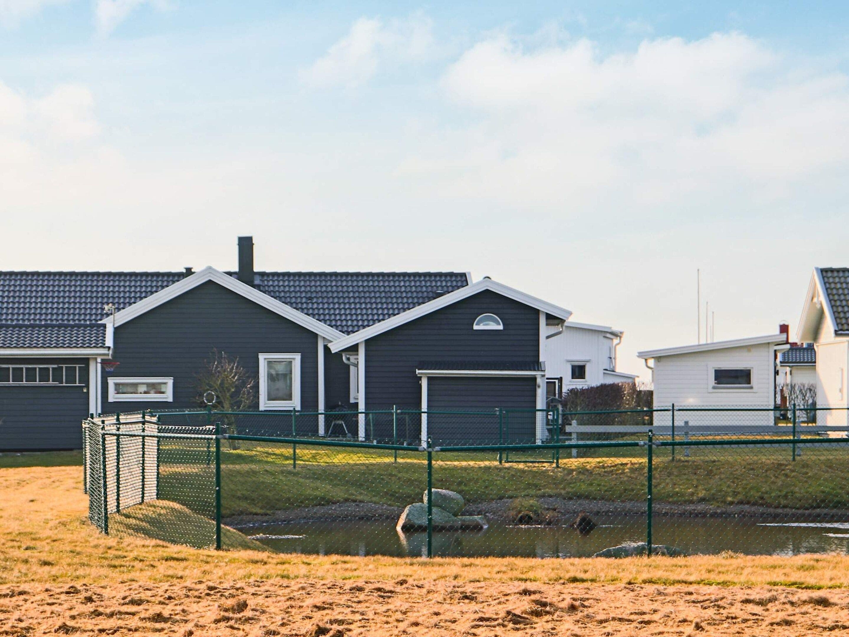A residential area with houses, a fenced sports court, and a small water feature.