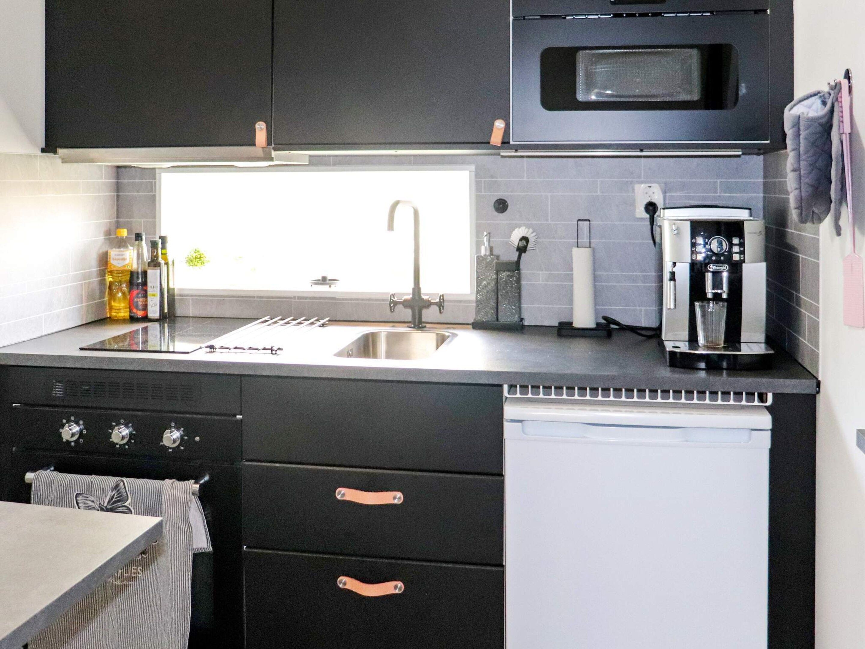 Una cocina moderna con microondas integrado, lavaplatos de acero inoxidable y cafetera.