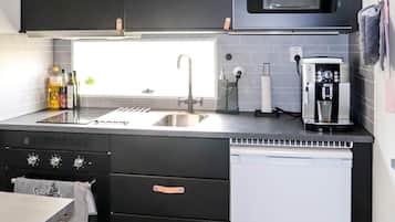 Una cocina moderna con microondas integrado, lavaplatos de acero inoxidable y cafetera.