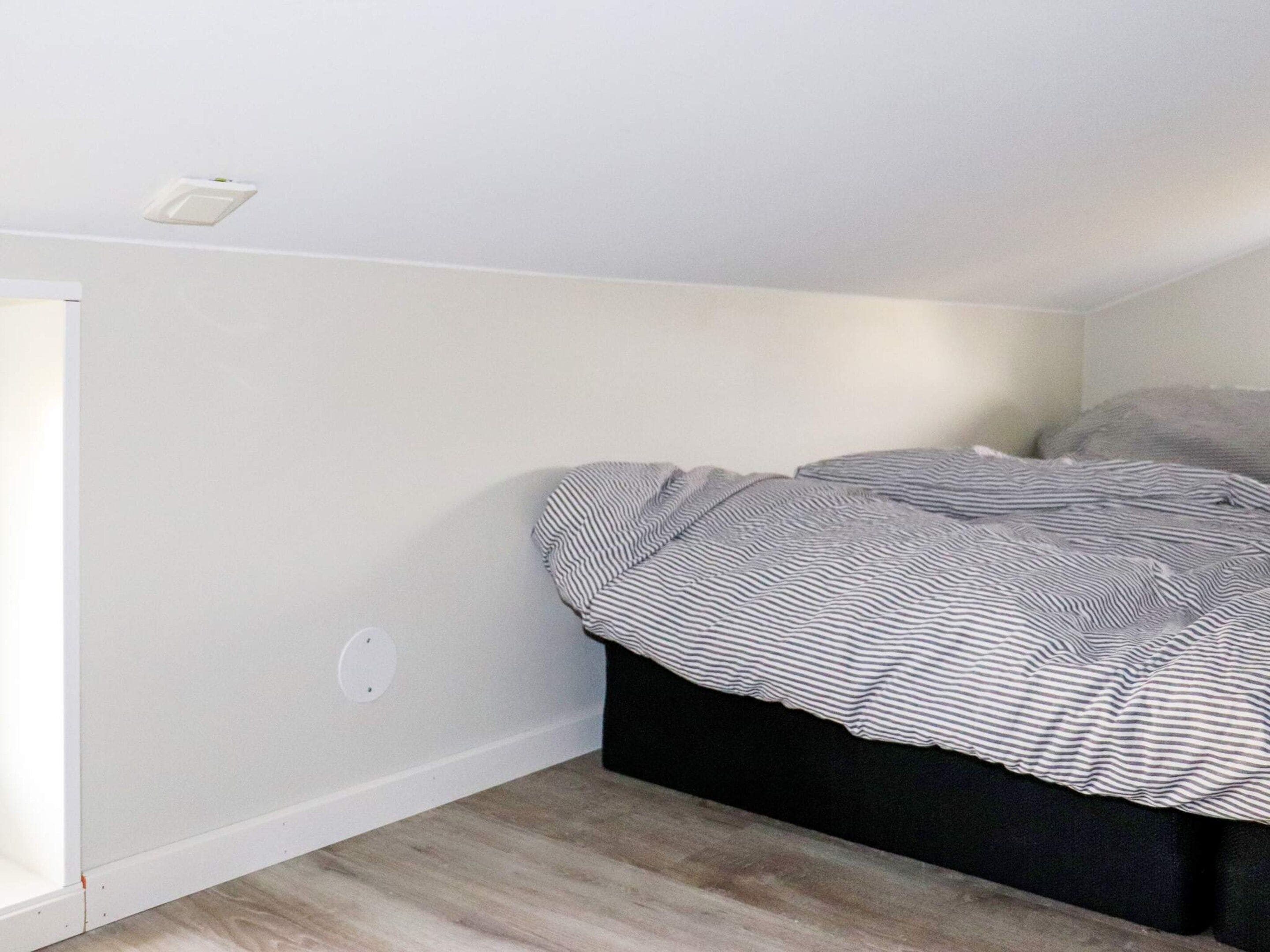 A bedroom with a bed, a window, and a wall socket.