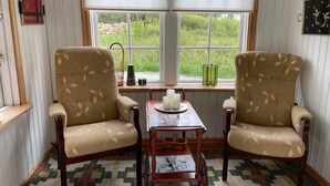 A corner room with two armchairs, a small table with a candle, and a window with a view of greenery. - 6 Person Holiday Home in Tingsryd-by Traum (Tingsryd)