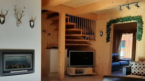 Ett modernt vardagsrum med en öppen spis, en tv och en trappa.
