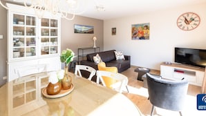 Un salon moderne comprenant un coin repas, un canapé, un téléviseur et une horloge décorative.