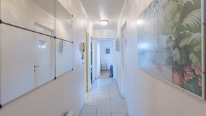 A narrow hallway with white walls, a tiled floor, and a large floral mural on one side. - Retreat With Pool Access (Middelkerke)