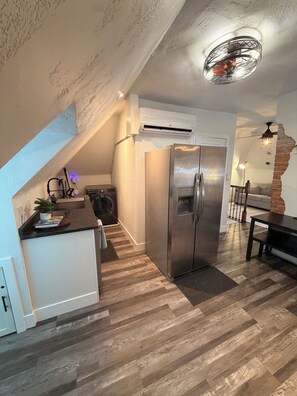 A modern kitchen with a built-in refrigerator, a dining area with a brick accent wall, and a ceiling fan. - One of the oldest houses in Butler, with an updated vibe. (Butler)