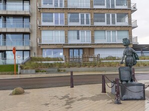 Un bâtiment moderne doté de nombreux balcons et orné d’une statue représentant une figure tenant une valise.