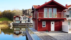 Une propriété située au bord de l’eau, avec un bâtiment rouge doté d’un balcon et d’une jetée qui s’avance dans l’eau.