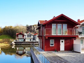 A waterfront property with a red building featuring a balcony and a dock extending into the water. - 4 Star Holiday Home in Hamburgsund (Hamburgsund)