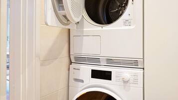 Lavadora y secadora apiladas en una habitación con paredes blancas.