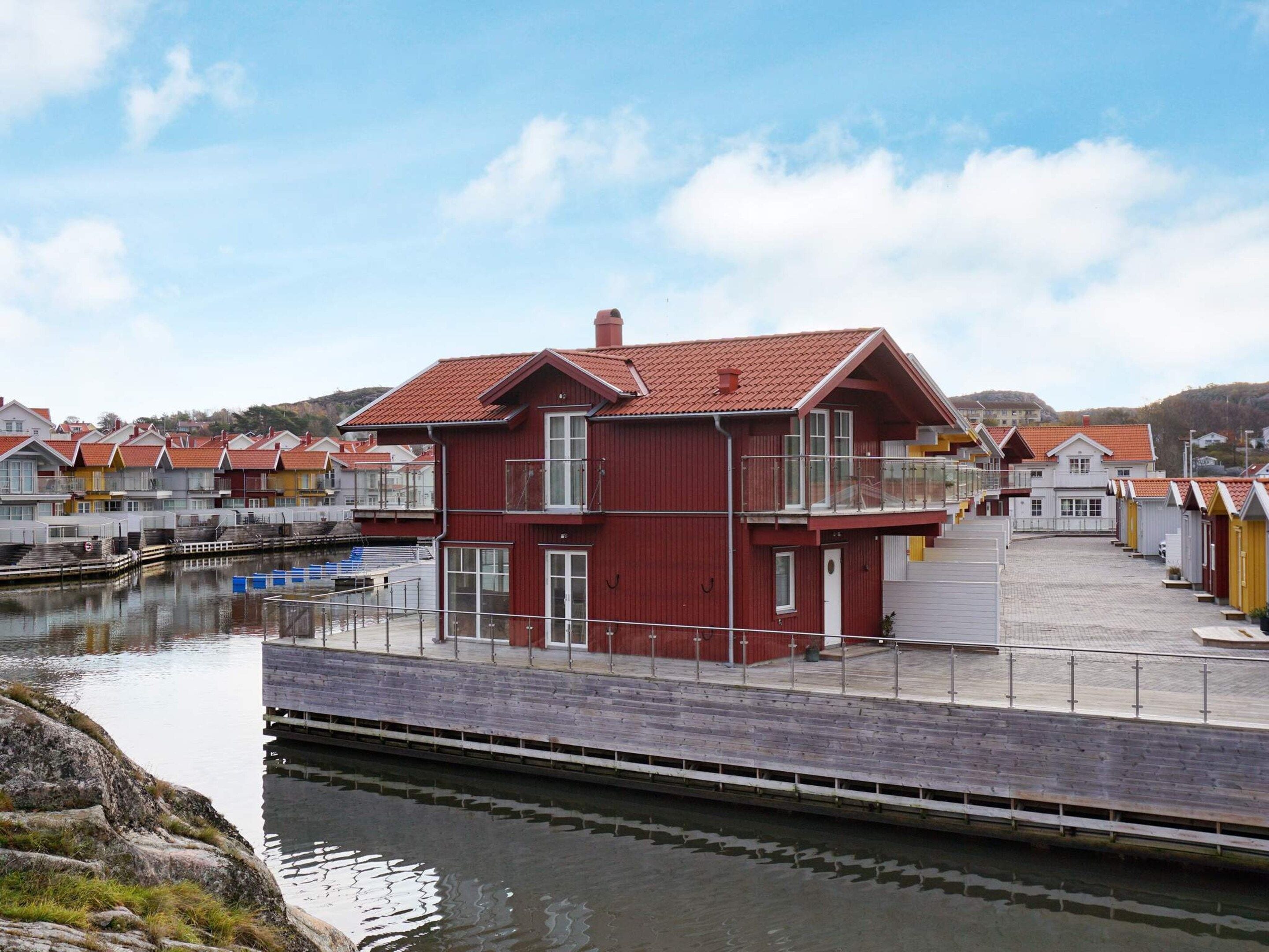 A red building with a balcony, situated next to a water body with a dock.