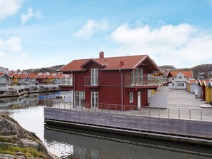 Un bâtiment rouge doté d’un balcon, situé à côté d’un plan d’eau muni d’un quai.