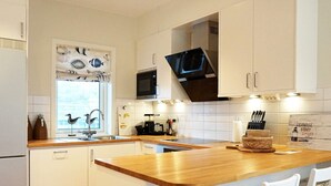Eine Küche mit weißen Schränken, einer Holz Arbeitsplatte, einer Mikrowelle, einem Spülbecken und einem Fenster mit Blick nach draußen.