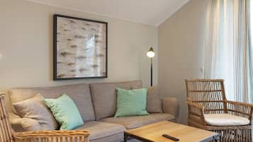 Uma sala de estar com sofá, duas poltronas, mesa de centro, abajur e quadro na parede.