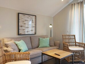 Un salon comprenant un canapé, deux fauteuils, une table basse, un lampadaire et un tableau encadré accroché au mur.