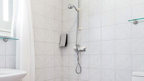 A bathroom with white tiles, a glass shower enclosure, a toilet, and a sink. - Holiday Home With Nature Access (Nexø)