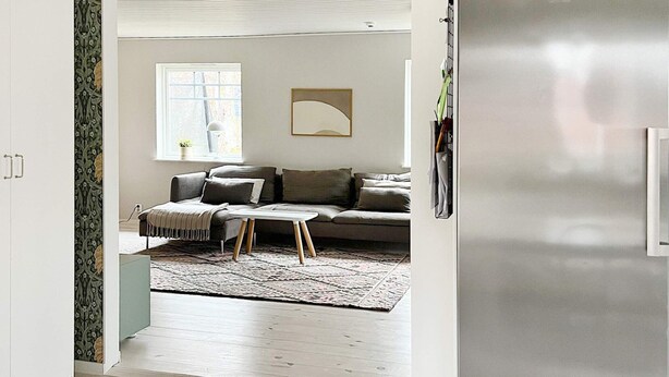 A modern living room with a grey sofa, a small white table, and a patterned rug. - 6 Person Holiday Home in Ljungby (Ljungby)