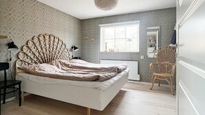 A bedroom with a unique headboard, a large window, a radiator, and a chair. - 6 Person Holiday Home in Ljungby (Ljungby)