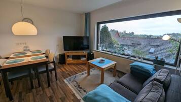 A modern living room with a TV, sofa, and dining area.